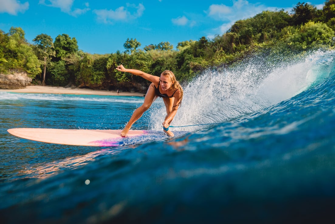 Beautiful surfer girl on surfboard. Woman in ocean during surfing in Bali